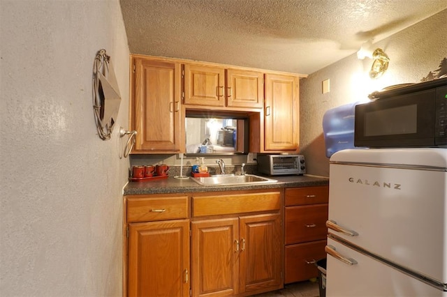 kitchen featuring refrigerator, sink, and a textured ceiling