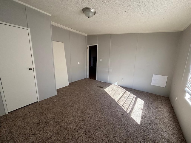 unfurnished room with ornamental molding, a textured ceiling, and carpet flooring