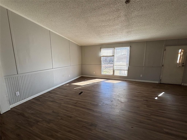 unfurnished room featuring dark wood-type flooring and a textured ceiling