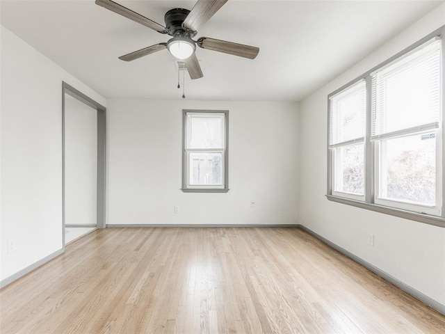 empty room with ceiling fan, light wood-type flooring, and a wealth of natural light