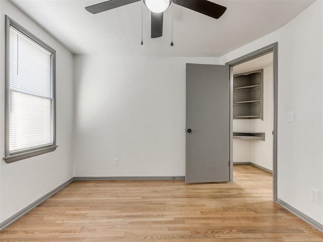 unfurnished bedroom with a walk in closet, light hardwood / wood-style flooring, a closet, and ceiling fan