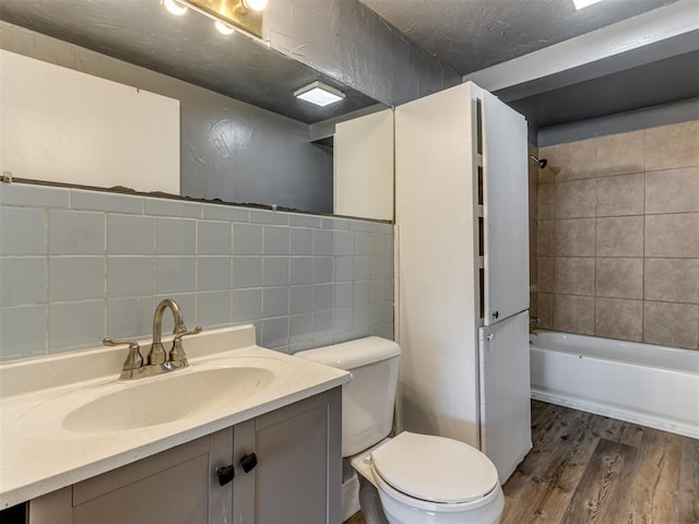 full bathroom featuring toilet, tasteful backsplash, tiled shower / bath, vanity, and hardwood / wood-style floors