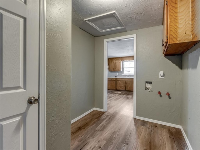 corridor featuring light wood-type flooring and a textured ceiling