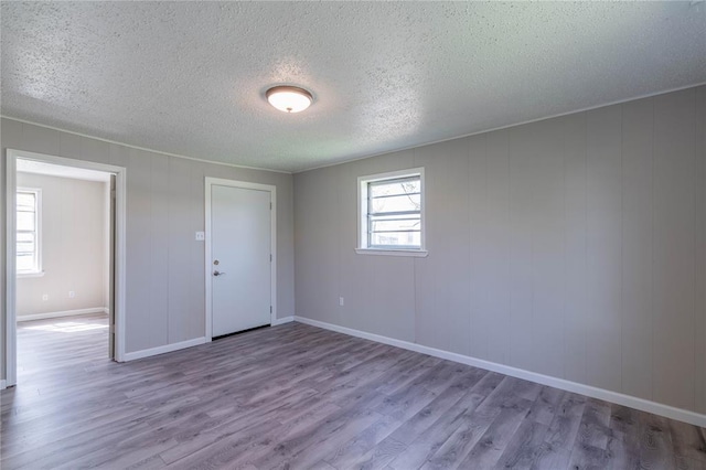 unfurnished room with a textured ceiling and light wood-type flooring