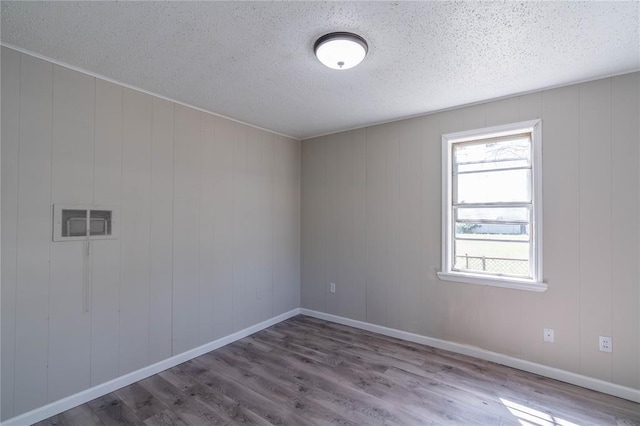 empty room featuring hardwood / wood-style floors, a textured ceiling, and wood walls