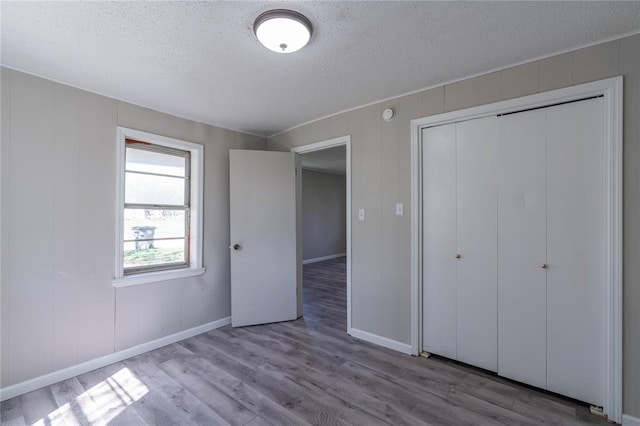 unfurnished bedroom featuring a closet, a textured ceiling, and light wood-type flooring