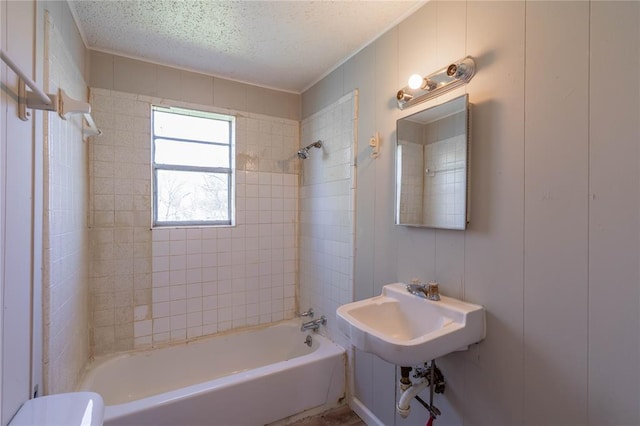 full bathroom with sink, tiled shower / bath combo, toilet, and a textured ceiling