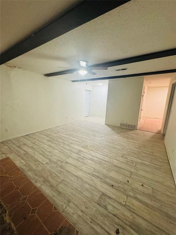 spare room featuring a textured ceiling, light wood finished floors, visible vents, and a ceiling fan