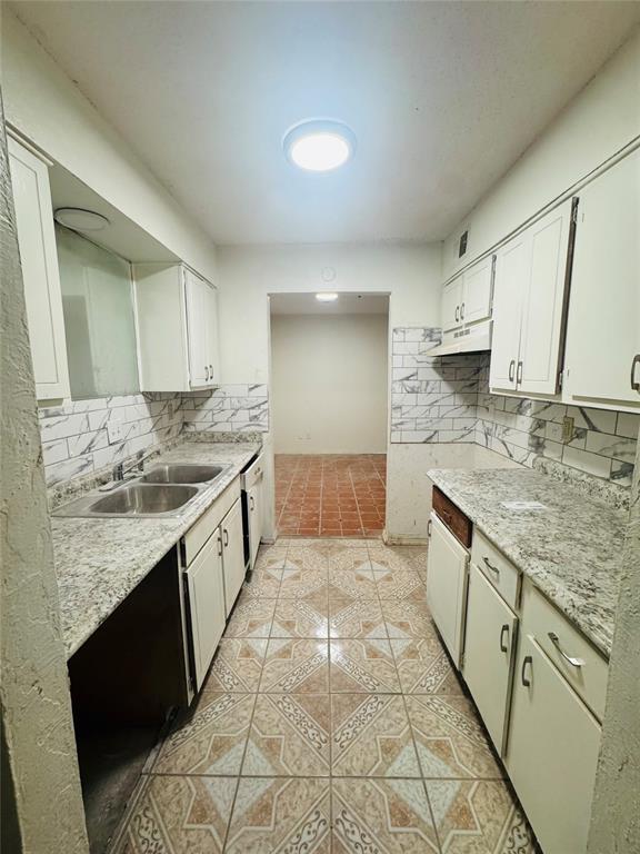 kitchen featuring light tile patterned floors, tasteful backsplash, a sink, and white cabinetry