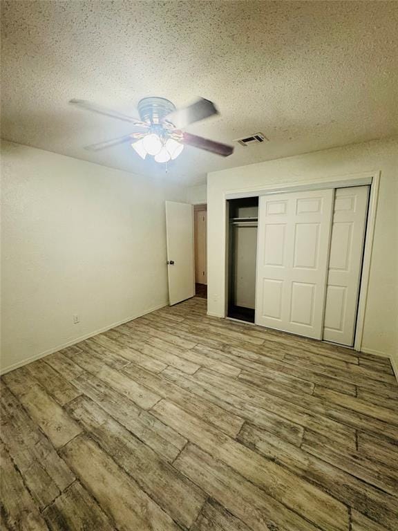 unfurnished bedroom featuring light wood finished floors, a closet, a ceiling fan, and a textured ceiling