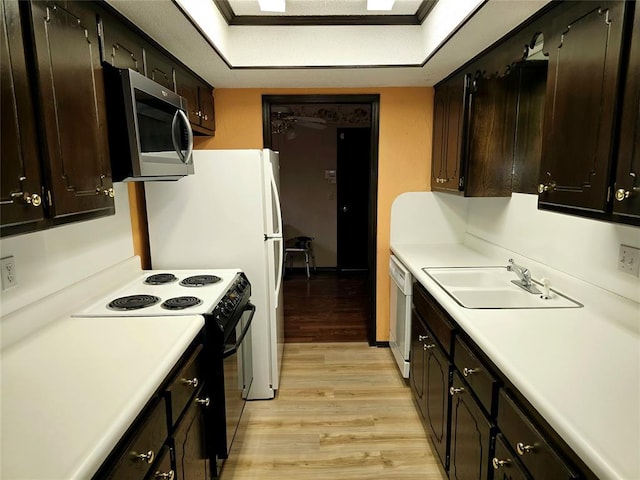 kitchen with dishwasher, sink, dark brown cabinets, light wood-type flooring, and black / electric stove