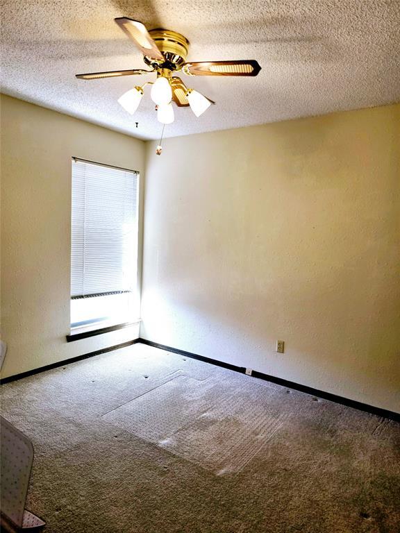 carpeted empty room with ceiling fan and a textured ceiling