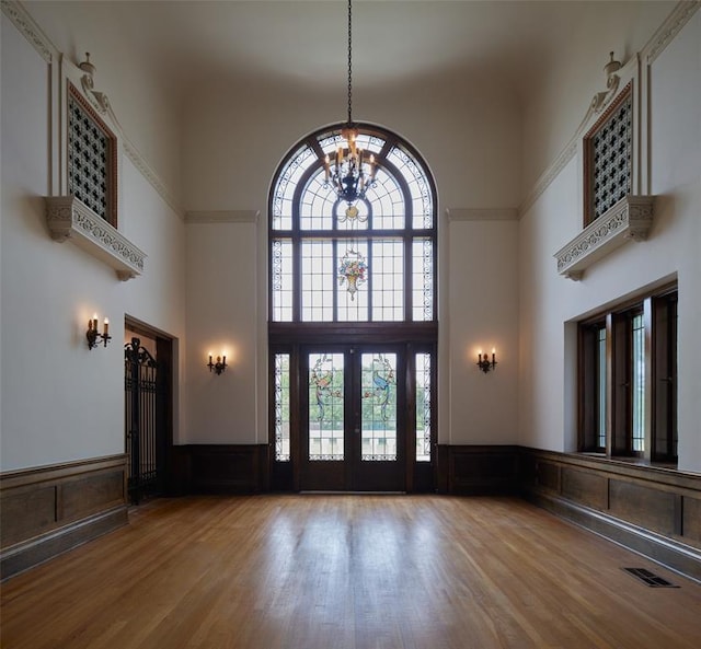 entrance foyer featuring french doors, a towering ceiling, wood-type flooring, and a chandelier