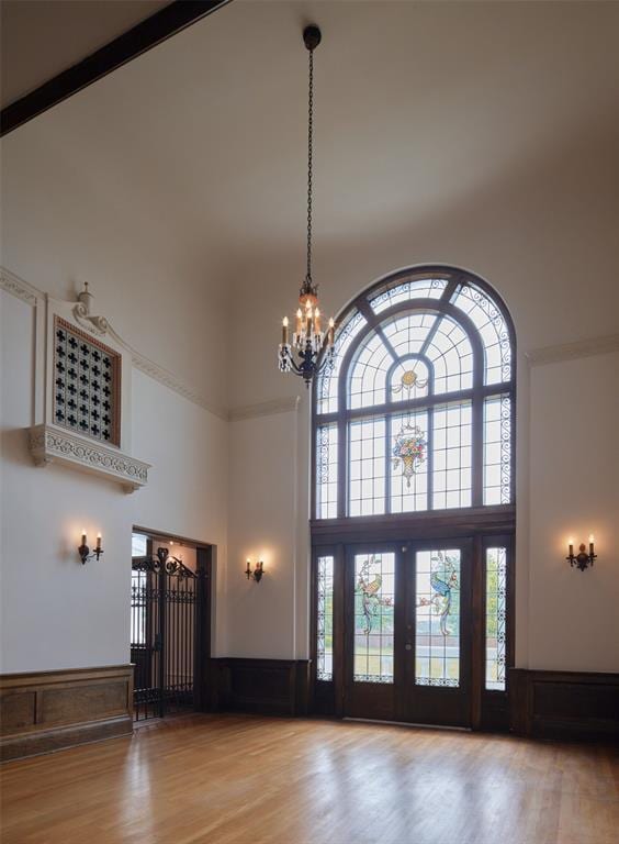 foyer entrance with a towering ceiling, hardwood / wood-style floors, and a notable chandelier