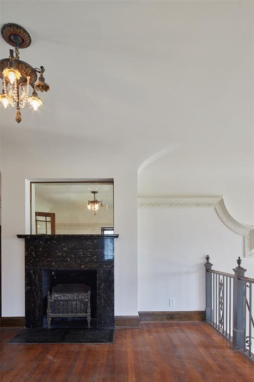 unfurnished living room with dark hardwood / wood-style floors, a fireplace, a chandelier, and crown molding