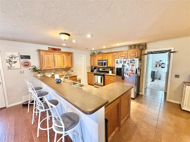 kitchen featuring sink, a breakfast bar, appliances with stainless steel finishes, light tile patterned flooring, and kitchen peninsula