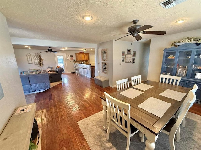 dining room featuring ceiling fan, hardwood / wood-style flooring, and a textured ceiling