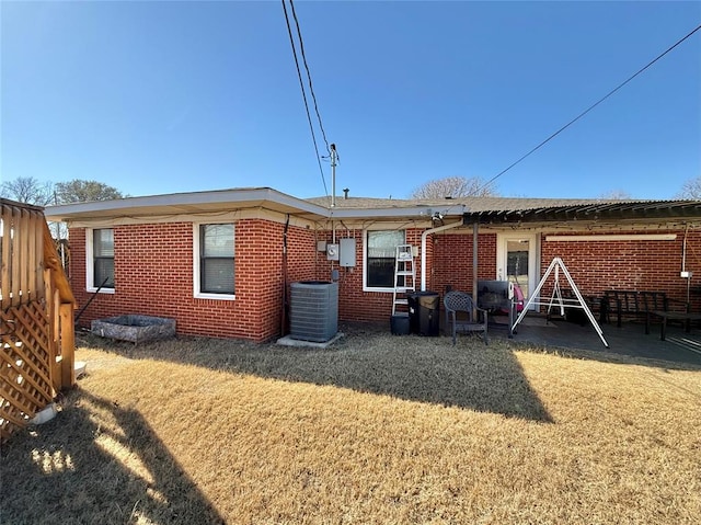 back of house with central AC unit and a lawn