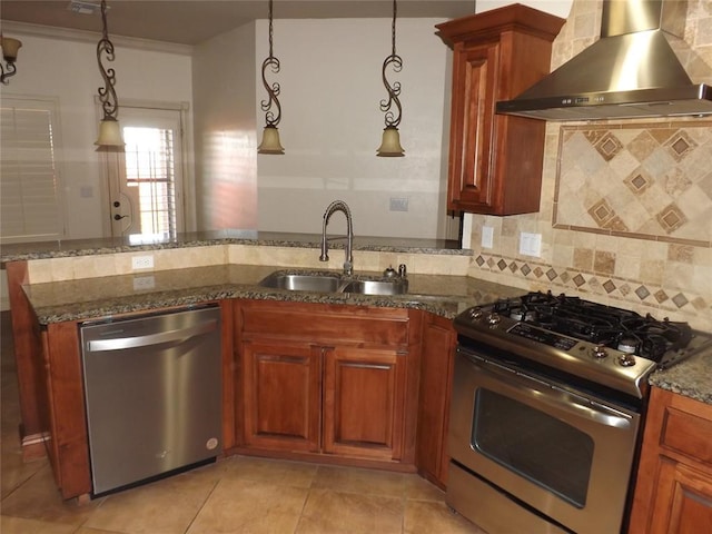 kitchen with appliances with stainless steel finishes, tasteful backsplash, sink, hanging light fixtures, and wall chimney exhaust hood