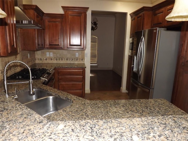 kitchen with wall chimney exhaust hood, sink, stainless steel appliances, light stone countertops, and decorative backsplash