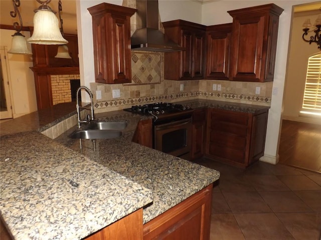 kitchen featuring gas range, sink, stone countertops, and wall chimney exhaust hood