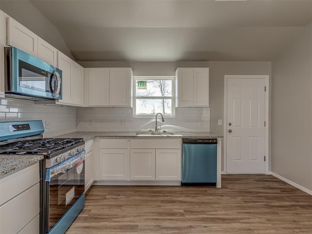 kitchen featuring sink, light stone counters, light hardwood / wood-style flooring, stainless steel appliances, and white cabinets