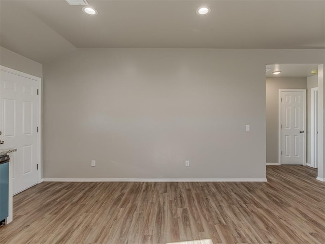 spare room with lofted ceiling and light wood-type flooring