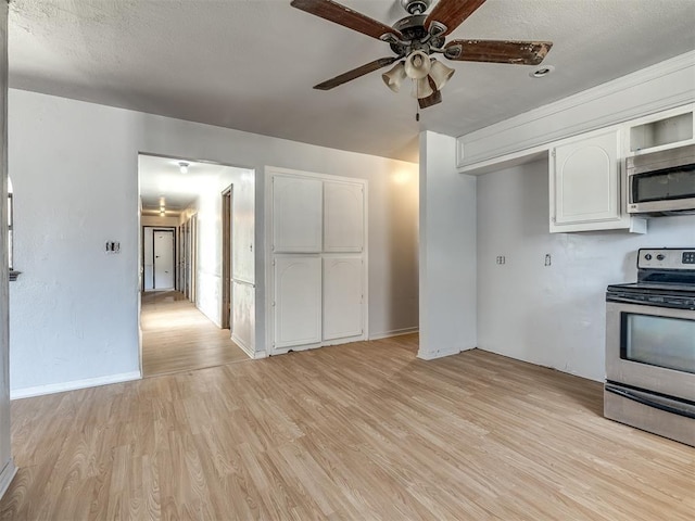 kitchen featuring stainless steel appliances, white cabinetry, ceiling fan, and light hardwood / wood-style flooring