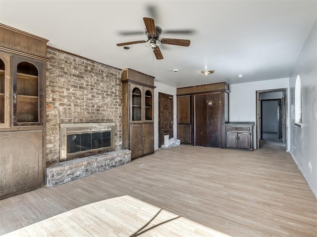 unfurnished living room featuring ceiling fan, a fireplace, and light hardwood / wood-style flooring