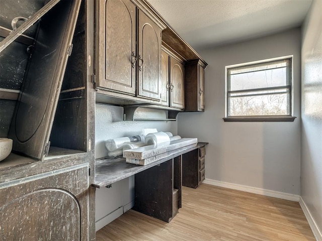 interior space featuring a textured ceiling, dark brown cabinetry, and light hardwood / wood-style flooring