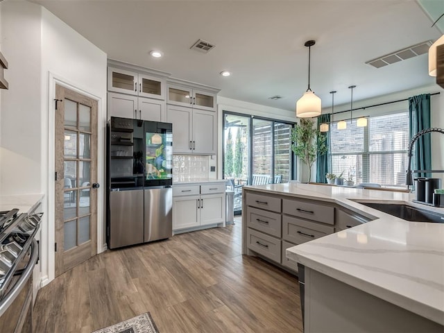 kitchen with white cabinetry, light stone counters, decorative light fixtures, appliances with stainless steel finishes, and decorative backsplash