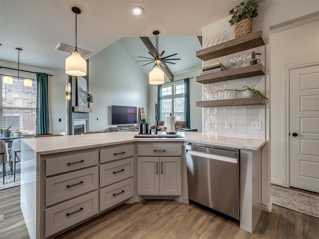 kitchen featuring pendant lighting, wood-type flooring, decorative backsplash, vaulted ceiling, and stainless steel dishwasher