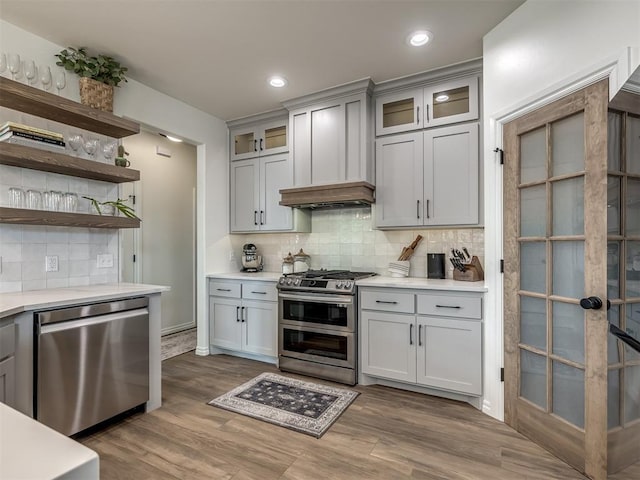 kitchen featuring tasteful backsplash, hardwood / wood-style floors, gray cabinetry, and appliances with stainless steel finishes