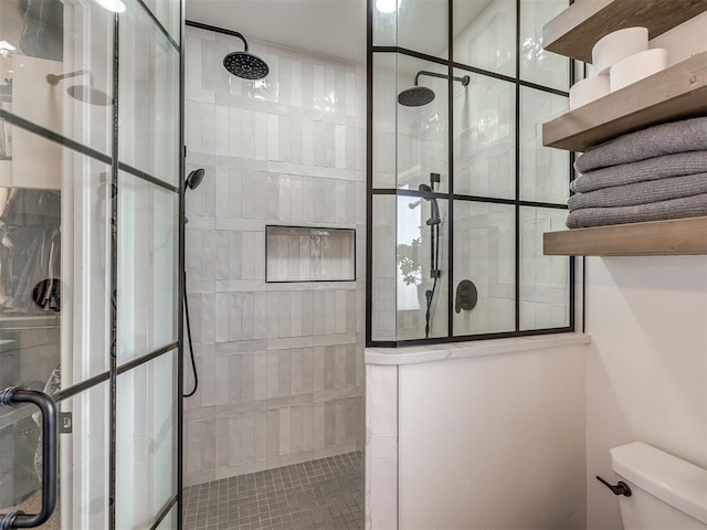 bathroom featuring tiled shower and toilet