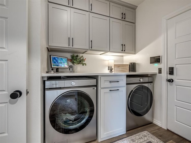 laundry area featuring cabinets, dark wood-type flooring, and washing machine and clothes dryer