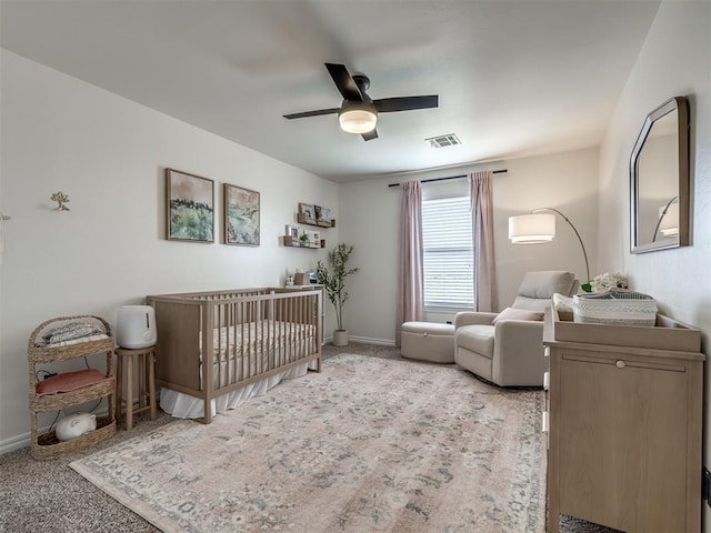 bedroom featuring ceiling fan, light carpet, and a crib