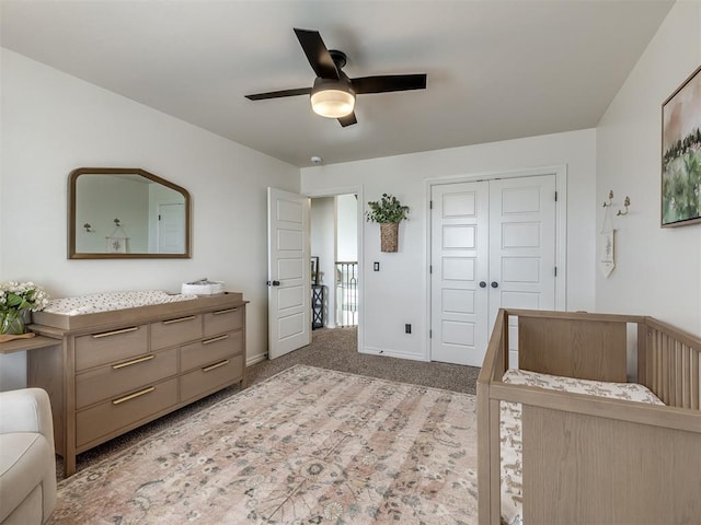 bedroom featuring light carpet, ceiling fan, and a closet