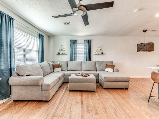 living room featuring a textured ceiling, light hardwood / wood-style flooring, and a healthy amount of sunlight