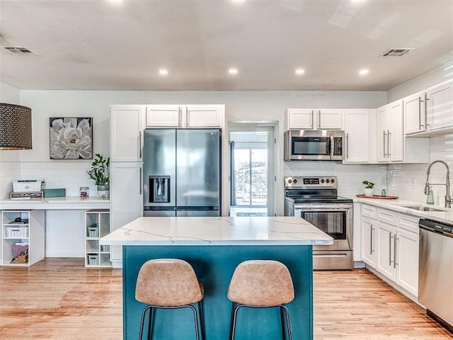 kitchen with white cabinetry, stainless steel appliances, a center island, and sink