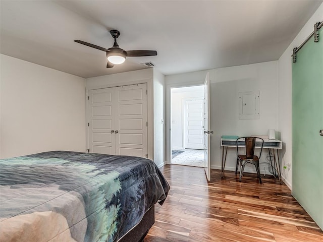 bedroom featuring ceiling fan, wood-type flooring, and electric panel