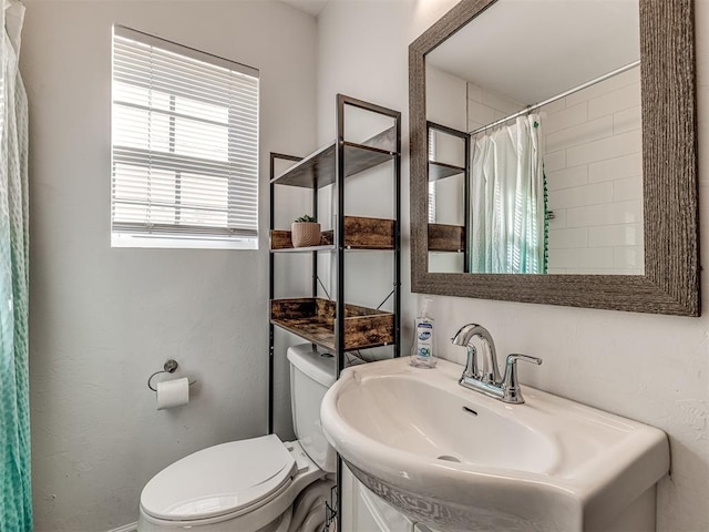 bathroom featuring walk in shower, sink, and toilet