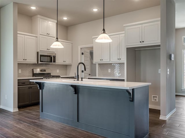 kitchen with stainless steel appliances, white cabinetry, and a kitchen island with sink