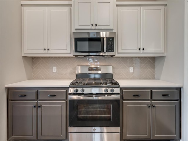 kitchen with white cabinetry, decorative backsplash, gray cabinetry, and appliances with stainless steel finishes