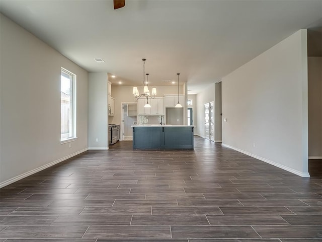 unfurnished living room with plenty of natural light and a notable chandelier