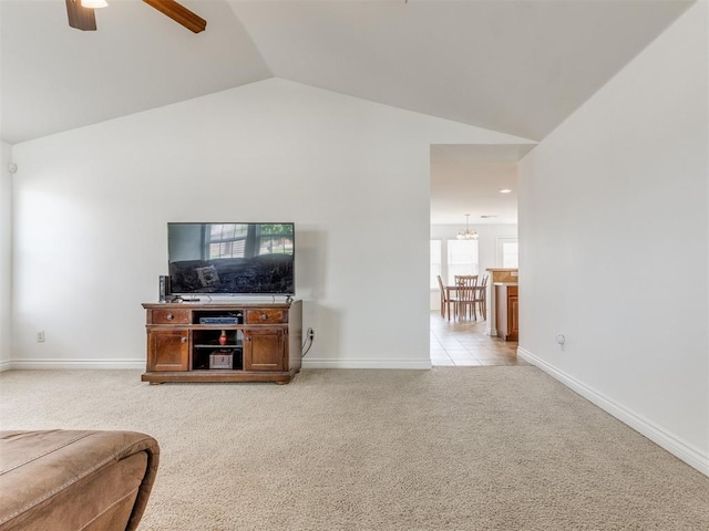 living room with vaulted ceiling, ceiling fan with notable chandelier, and light colored carpet