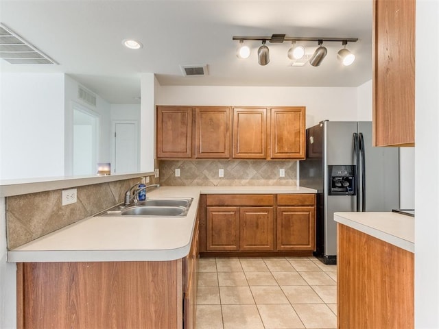 kitchen with stainless steel refrigerator with ice dispenser, sink, light tile patterned floors, kitchen peninsula, and decorative backsplash