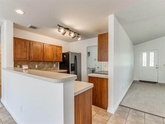 kitchen with stainless steel fridge with ice dispenser, light carpet, kitchen peninsula, washing machine and dryer, and backsplash