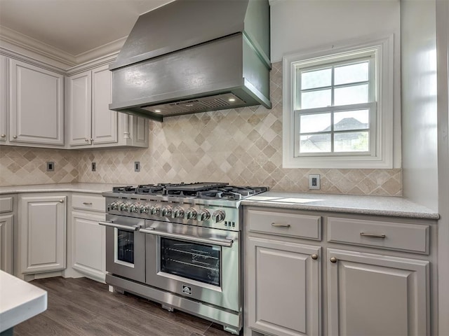 kitchen with white cabinets, dark hardwood / wood-style floors, range with two ovens, and wall chimney range hood