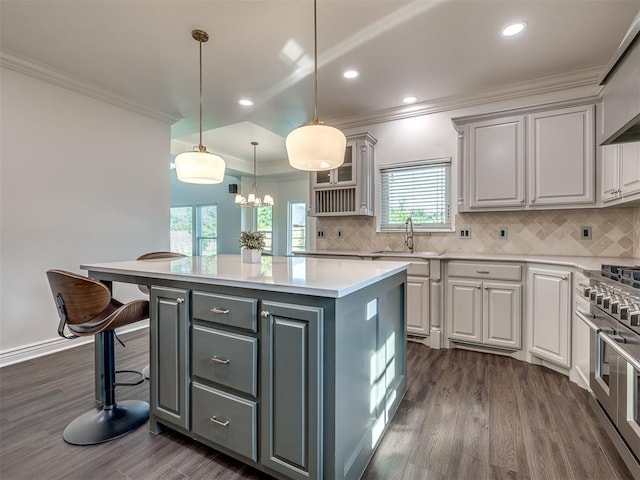 kitchen featuring a breakfast bar, gray cabinetry, decorative light fixtures, a center island, and double oven range