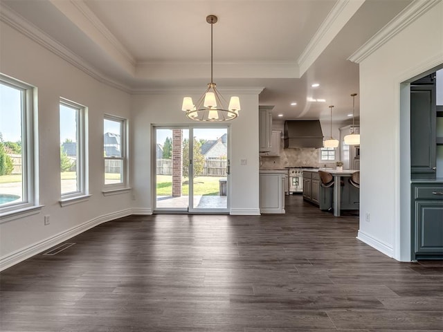 interior space with a raised ceiling, ornamental molding, dark hardwood / wood-style floors, and a chandelier